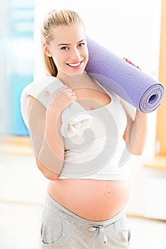 Pregnant woman holding yoga mat