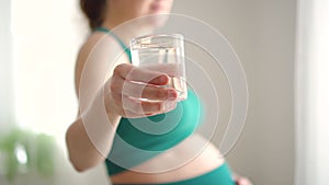 Pregnant woman holds a glass of water in her hand. Healthy lifestyle during pregnancy