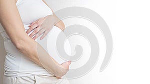 Pregnant woman holds hands on belly on light background. Pregnancy, maternity, preparation and expectation concept. Close-up, copy