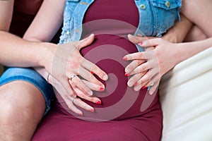 Pregnant woman holds hands on her belly, close-up. Concept of prenatal period, maternal health