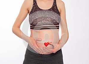 Pregnant woman holds a heart symbol near her belly