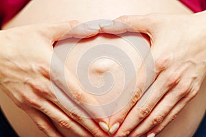 Pregnant woman holds her hands in her stomach. Third trimester. Pregnancy. Waiting for a miracle. Motherhood