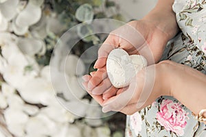 A pregnant woman holds in her hands a white heart. The heart is