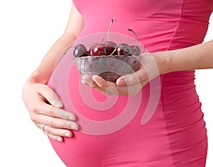 Pregnant woman holds a plate with cherry