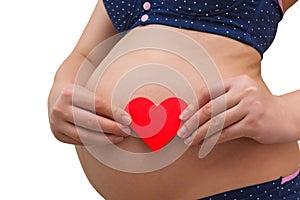 A pregnant woman holds a red heart symbol on the background of her belly