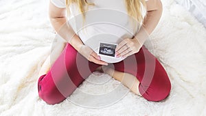 A pregnant woman holds a snapshot of an ultrasound in her hands. Selective Focus