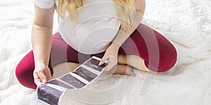 A pregnant woman holds a snapshot of an ultrasound in her hands. Selective Focus