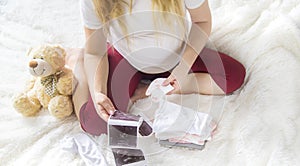 A pregnant woman holds a snapshot of an ultrasound in her hands. Selective Focus