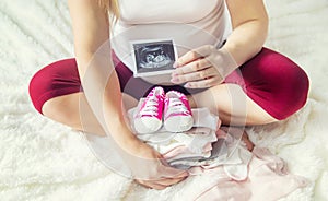 A pregnant woman holds a snapshot of an ultrasound in her hands. Selective Focus