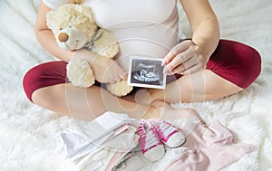 A pregnant woman holds a snapshot of an ultrasound in her hands. Selective Focus