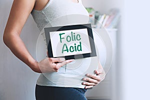 Pregnant woman holds whiteboard with text message - FOLIC ACID