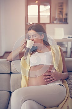 Pregnant woman at home drinking coffee.