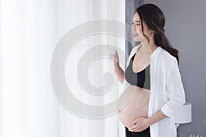 Pregnant woman at home looking outside the window