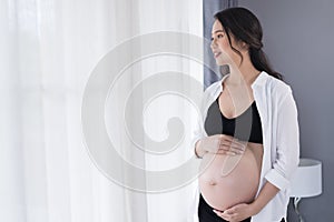 Pregnant woman at home looking outside the window