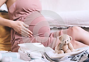 Pregnant woman hugging belly and packing maternity hospital bag. Beautiful mother during pregnancy waiting for baby preparing