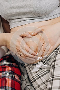 Pregnant woman husband create heart sign belly