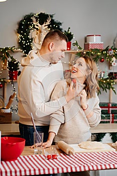 pregnant woman with husband in New Year kitchen prepare dough and eat cakes