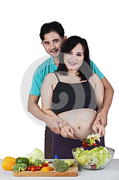 Pregnant woman with husband preparing salad