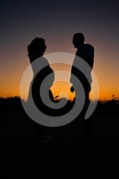 Pregnant woman and husband sihouettes in sunset