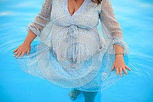 a pregnant woman husband swim in the pool.