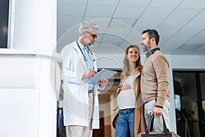 Pregnant woman and husband talking to obstetrician in hospital. Admitting woman in labor to maternity ward, planned