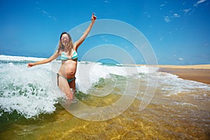 Pregnant woman jump in sea waves at the beach