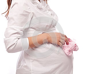 Pregnant woman keeping pink baby-shoes.