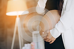 A pregnant woman keeps her hands on her stomach, supporting her unborn child