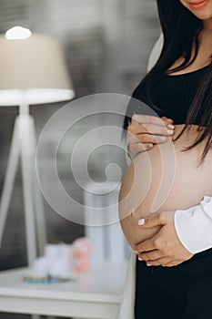 A pregnant woman keeps her hands on her stomach, supporting her unborn child