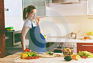 pregnant woman on kitchen making healthy salad