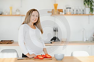 Pregnant woman in kitchen making salad