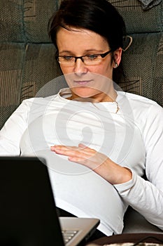 Pregnant woman with laptop in bed