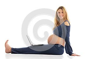 Pregnant woman with a laptop sitting on the floor