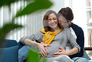 Pregnant woman laughing while feeling her baby pushing inside