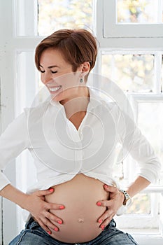 Pregnant Woman Laughs Touching Her Tummy With Her Hands