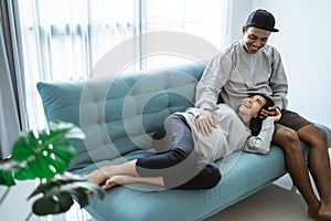 A pregnant woman lay on her husband`s lap while sitting relaxed