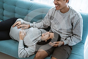 A pregnant woman lay on her husband`s lap while sitting relaxed