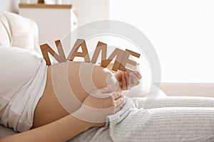 Pregnant woman with letters on belly, closeup. Choosing baby name