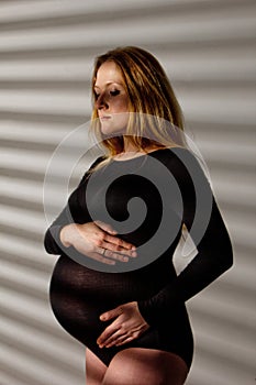 A pregnant woman in lingerie with a big belly in the ninth month of pregnancy is hugging her abdomen. in anticipation of