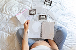 Pregnant woman list. Young pregnancy mother holding notepad. Pregnant lady writing check list of baby. Pregnancy