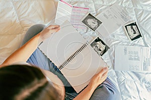 Pregnant woman list. Young pregnancy mother holding notepad. Pregnant lady writing check list of baby. Pregnancy