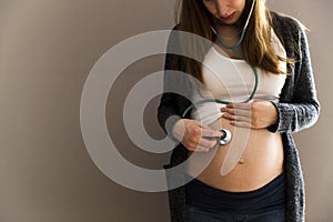 Pregnant woman listening her to her baby in the belly with with