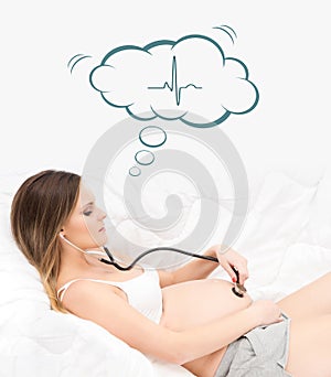 Pregnant woman listening to her belly with a stethoscope