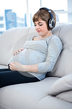 Pregnant woman listening to music while sitting in living room