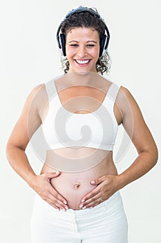 Pregnant woman listening to music while touching her belly