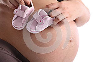 Pregnant woman with little baby shoes on her belly