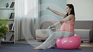 Pregnant woman living active lifestyle, doing exercises, pumping her muscles