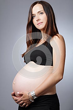 Pregnant woman with long dark hair in black dress.