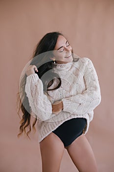 Pregnant woman with long hair in white sweater.