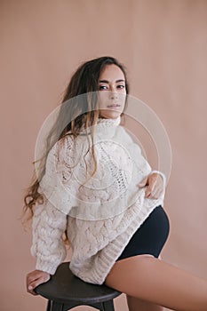 Pregnant woman with long hair in white sweater.